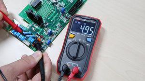 UNI-T UT123 Pocket Residential Digital Multimeter – EBTN Display, AC/DC Voltage, Resistance, Temperature, NCV, Diode & Continuity, One-Hand Design - a 4.95 kΩ reading on its EBTN display while probes test a green circuit board on a light-coloured surface.