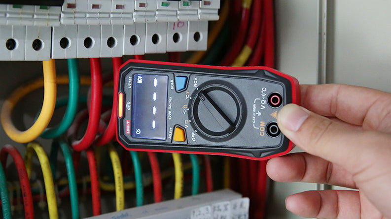 UNI-T UT123 Pocket Residential Digital Multimeter – EBTN Display, AC/DC Voltage, Resistance, Temperature, NCV, Diode & Continuity, One-Hand Design - held in a hand near electrical wires, showing a black and red body, rotary dial, and NCV display.