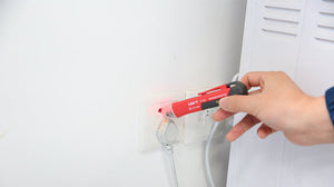 UNI-T UT12D Non-Contact AC Voltage Detector Pen – 24V to 1000V NCV Tester with LED Flashlight, Buzzer & LED Alert, Dual High/Low Sensitivity, Auto Power-Off, 1m Drop-Proof - red and black, held by a hand and testing a wall socket with its red LED indicator light illuminated.