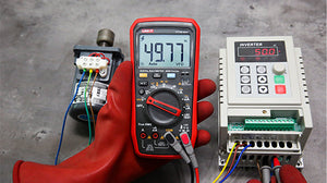 UNI-T UT18B MAX True RMS Digital Multimeter – 6000 Count, 1000V AC/DC, VFD, Temperature, LED Test, Capacitance, Frequency, EMI Protection with Gold-Plated Leads - held in a gloved hand, showing a 49.77 Hz reading on its display, next to a motor and an inverter.