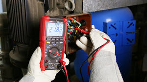 UNI-T UT195DS Professional Dual-Display Datalogging True RMS Digital Multimeter – 6000 Count, AC/DC 1000V, 20A, IP65 Waterproof, LoZ, Temperature, Flashlight, CAT III 1000V - held by gloved hands, showing a red casing, rotary dial, and a digital display reading 21.82 V while testing a motor.