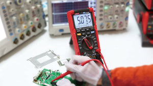 UNI-T UT195E Professional True RMS Digital Multimeter – 6000 Count, AC/DC 1000V, 20A, IP65 Waterproof, LoZ, Flashlight, 2m Drop-Proof, CAT III 1000V - in a red protective case, showing a 5.075 reading on the display while being used to test a green circuit board.
