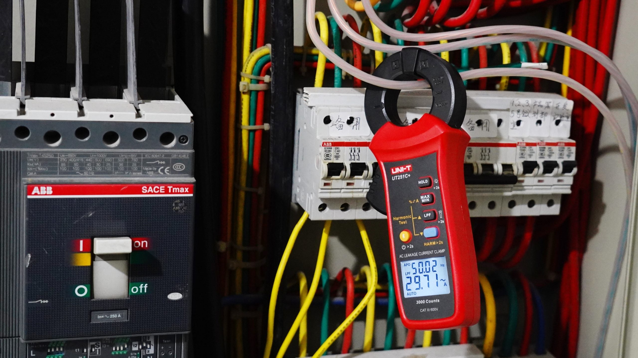 UNI-T UT251C+ AC Leakage Current Clamp Meter – 1µA Resolution, 3mA to 60A, 40mm Jaw, Harmonic Test, LPF, Bluetooth, Dual Display, CAT III 600V - clamped onto electrical wires, showing 50.02 and 29.71 on its digital display.