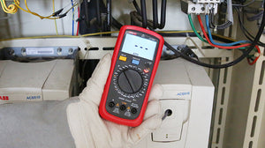 UNI-T UT39E+ High-Resolution Digital Multimeter – 20000 Count, AC/DC 1000V, 20A, High Accuracy 0.05%, Capacitance, NCV, hFE, CAT II 1000V / CAT III 600V - held in a gloved hand, showing a red casing, central rotary dial, input ports, and a display reading APO.