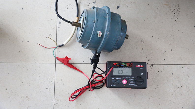 UNI-T UT526 Multifunction Electrical Tester – Multifunction Installation Tester, 250V/500V/1000V - connected to a grey cylindrical motor with red and black test leads, showing 0.01 on the digital display.