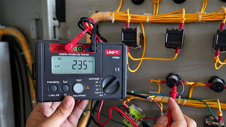 UNI-T UT582+ RCD / ELCB Tester – Digital RCD / ELCB Trip Tester - a digital display reading 235V, a rotary dial, control buttons, and connected red and black leads.