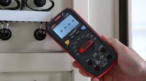 UNI-T UT60BT Bluetooth True RMS Digital Multimeter – 9999 Count, AC/DC 1000V, 10A, Wireless Data Logging via App, IP54, Temperature, NCV, CAT III 600V - held in a hand, showing its black and red casing, rotary dial, buttons, input ports, and a screen with dashed indicators.