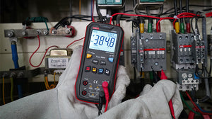 UNI-T UT60S True RMS Digital Multimeter – 9999 Count, AC/DC 1000V, 10A, Capacitance, Frequency, Temperature, NCV, 3-Color LED Alert, CAT III 600V - held in gloved hands, displaying 384.8V AC and 50.03Hz, with red and black probes connected to the bottom ports.
