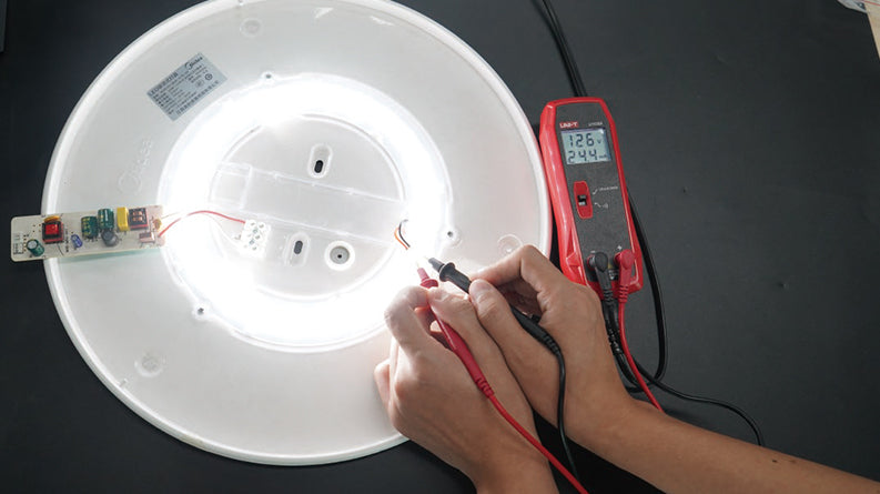 UNI-T UT659A LED Tester – 24V/300V Output, LED & LED-Driver Test, Continuity, AC 85–265V Input, CAT II 300V, Backlit LED Test Meter - red handheld meter displaying 126V and 24.4mA while testing a circular LED light board with two probes.