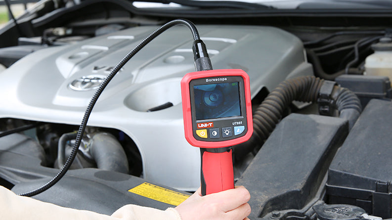 UNI-T UT665 Industrial Borescope – 2.4" TFT Screen, 9mm Camera Probe, 1m Semi-Rigid, IP67, 4 LED, Inspection Endoscope Camera - with a red handle, screen, and four control buttons, showing a live internal view of a car engine.