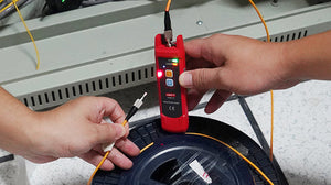 UNI-T UT691-10 Visual Fault Locator – 10mW Red Laser, 8–10km Range, 650nm, 2.5mm FC Connector, Continuous/Pulse, Rechargeable Fiber Optic VFL Pen - handheld device with two buttons and a glowing red indicator light, held while testing an optical fiber cable.