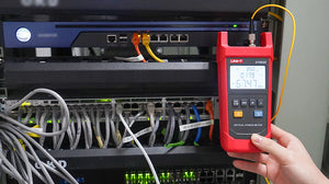 UNI-T UT692G High-Power Optical Power Meter – -50~+26DBM, 800–1700nm, FC/SC/ST, InGaAs, ±5%, IP65, Fiber Optic Power Meter - a red handheld device with a screen showing 850nm and -67.47 dBm, connected by a yellow fiber cable in a server rack.