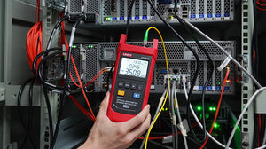 UNI-T UT693D Optical Multimeter – Fiber Power Meter (-70~10DBM, 800–1700nm) + 10mW VFL, FC/SC/ST, InGaAs, IP65, Optical Power Meter & Fault Locator - held in a hand, showing a red casing, buttons, and a digital display reading -36.08 dBm connected to a fiber optic cable.