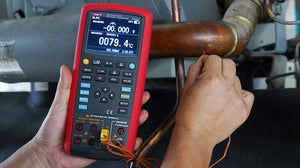UNI-T UT725 Multifunction Process Calibrator – mA, V, Temperature (TC/RTD), Frequency, Resistance, Pulse Source &amp; Measure, 20000 Count - with buttons, ports, and a screen displaying 0079.4°C held by a person measuring a copper pipe.