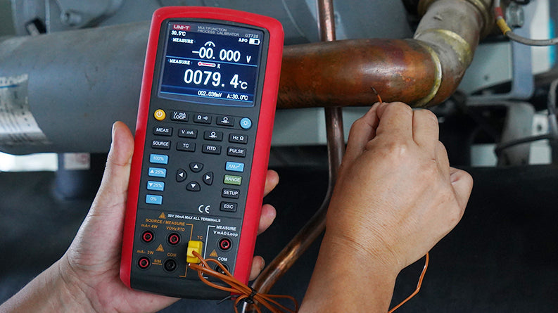 UNI-T UT725 Multifunction Process Calibrator – mA, V, Temperature (TC/RTD), Frequency, Resistance, Pulse Source &amp; Measure, 20000 Count - with buttons, ports, and a screen displaying 0079.4°C held by a person measuring a copper pipe.