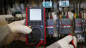 UNI-T UT81B Handheld Scopemeter – 8MHz Oscilloscope + 4000 Count Digital Multimeter, 40MS/S, AC/DC 1000V, Waveform Storage, USB, 2-in-1 Test Tool - by gloved hands, showing a black and red casing, control buttons, a rotary dial, and a screen displaying a waveform.
