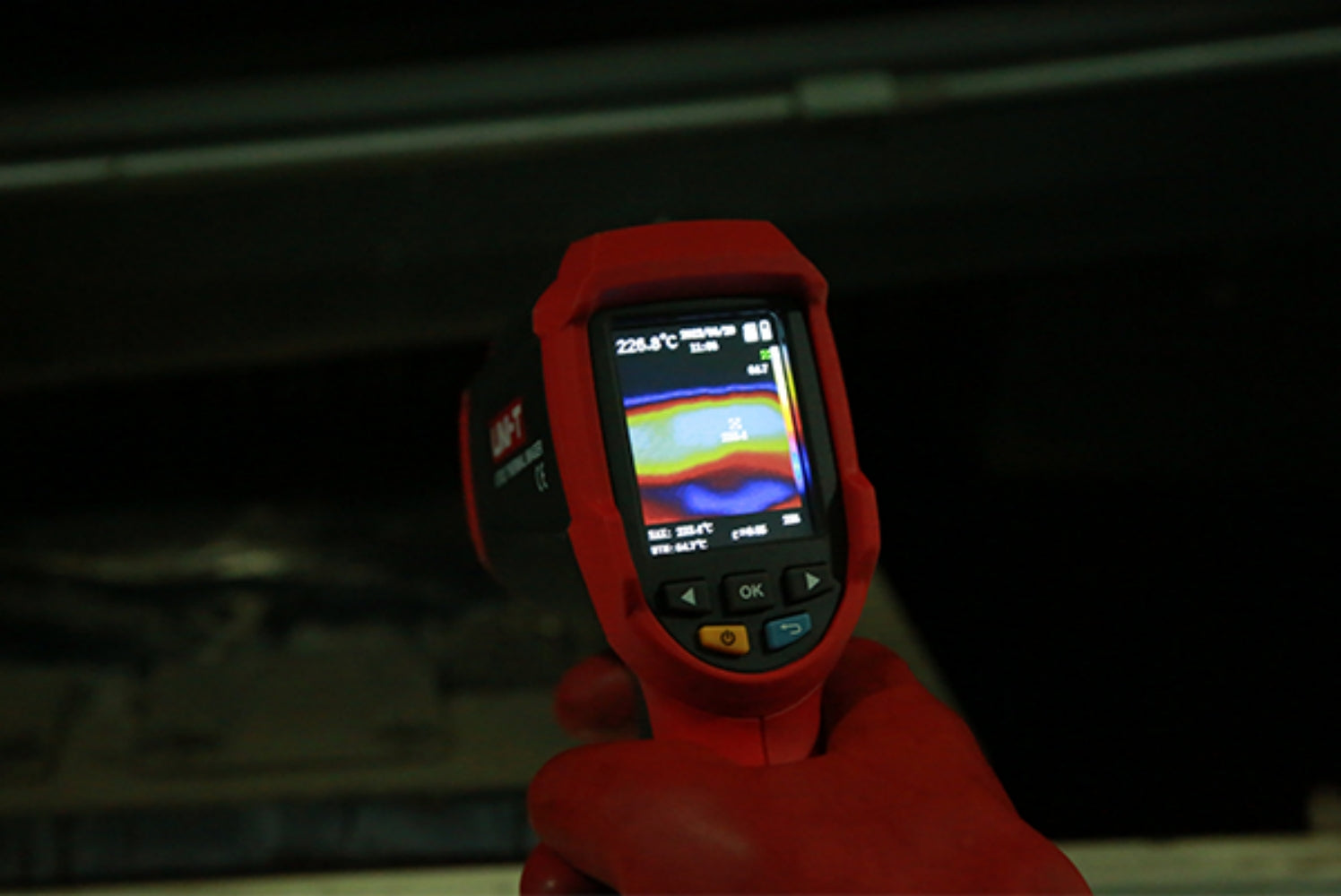 UNI-T UTI32 High Temperature Thermal Camera – 32×32, -20°C to 1000°C, 0.15°C - held in a gloved hand, showing a red casing, navigation buttons, and a screen displaying a thermal heat map and temperature.