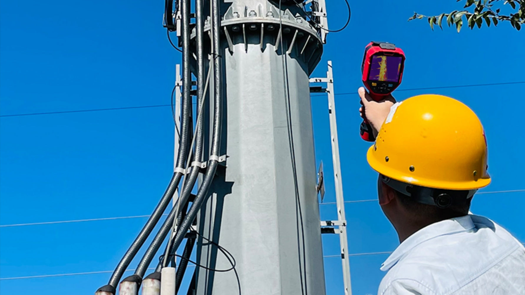 UNI-T UTI720E Enhanced Thermal Camera – 256×192, -20°C to 550°C, ≤50MK - held by a worker pointing at a utility pole, showing a colorful heat map on its digital display screen.
