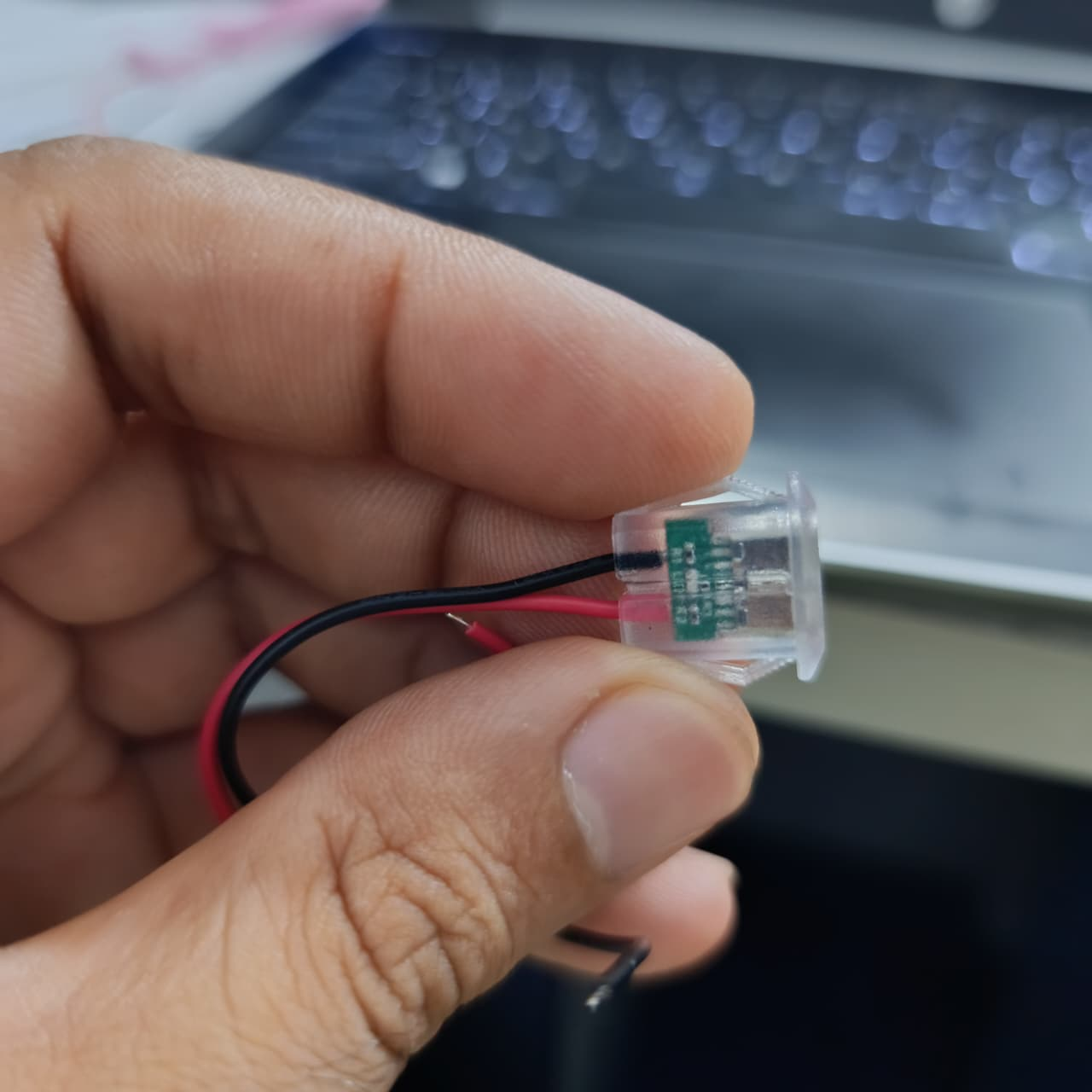 USB Type-C Oval LED Female Socket with Wires for Arduino Pakistan - hand holding a clear plastic oval socket with red and black wires attached.