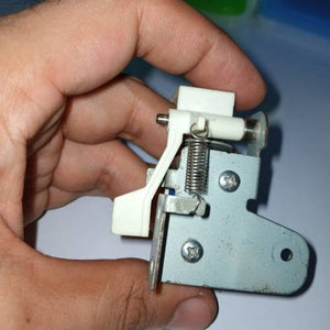 Used 1 Piece DC Solenoid Electromagnet In Mix Shape - a close-up of a metal and white plastic solenoid mechanism with an attached tension spring.