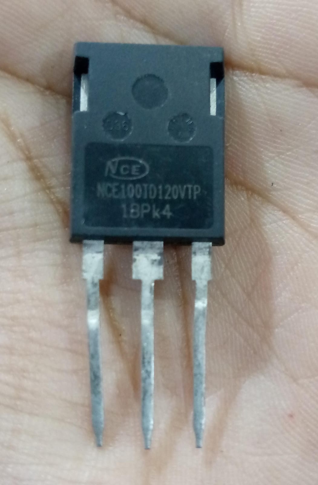 USED 1200V 100A NCE100TD120VTP Trench Fs II Fast IGBT – High-Performance Module for PV Power Systems - a black three-pin electronic component held in a hand with the model number printed on its front surface.