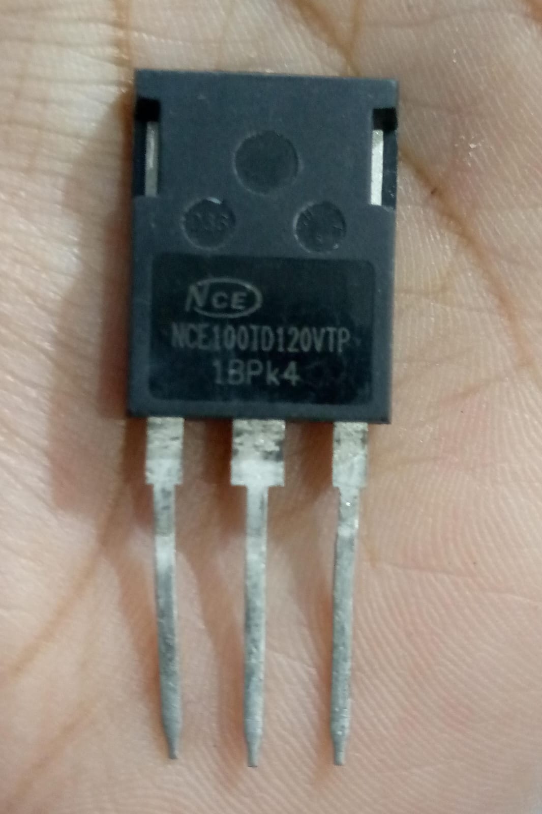 USED 1200V 100A NCE100TD120VTP Trench Fs II Fast IGBT – High-Performance Module for PV Power Systems - a black three-pin electronic component held in a hand, showing the printed model number on its face.