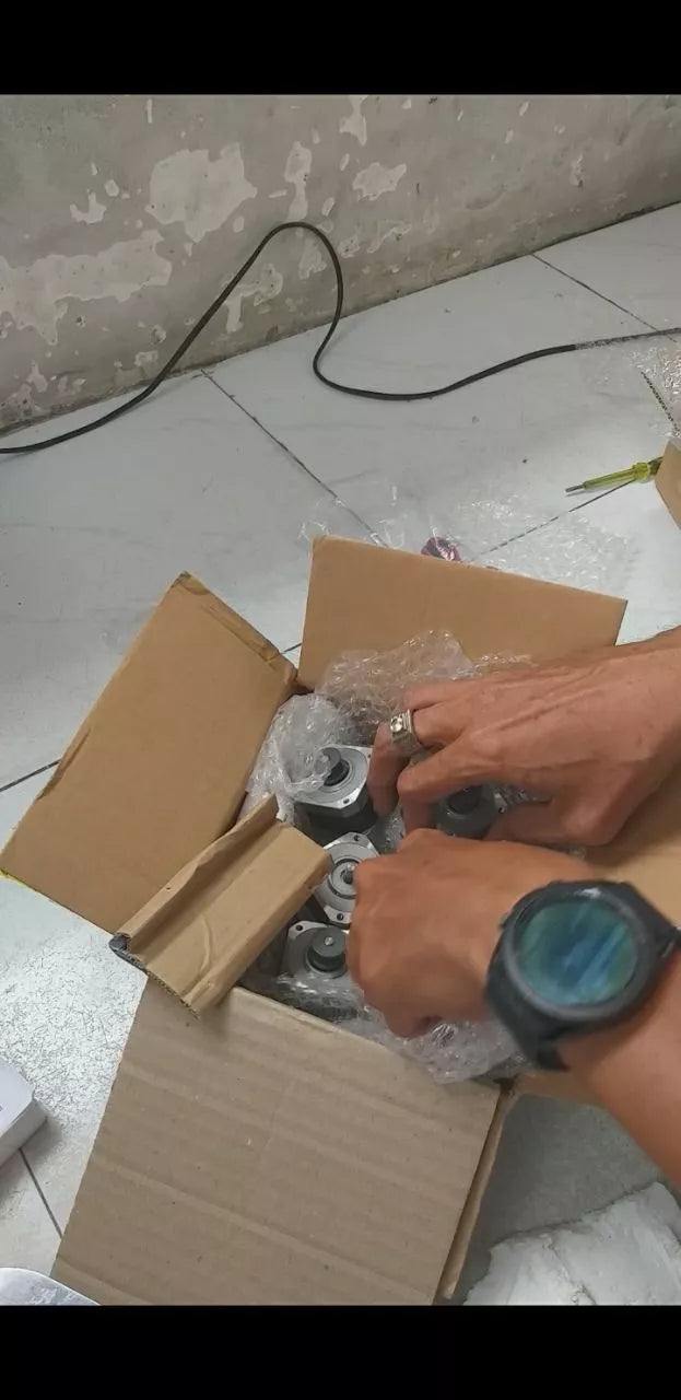 Used 4 Wire NEMA 17 5mm Shaft Bipolar Stepper Motors - shown inside a cardboard shipping box with bubble wrap, being handled by a person.
