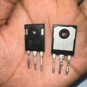 Used 80A 650V GWA80H65DFB (STGWA80H65DFB) – IGBT TO‑247-Digilog.pk - close-up view of two black TO-247 packaged transistors held in a hand, showing the front markings and rear metal mounting plates.