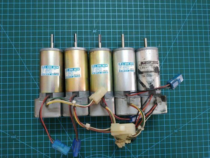 Used DC Servo Motor With Encoder High Speed 24V DC DSE38BE27-001IN Pakistan - five cylindrical metal motors with attached wires and connectors on a green grid.