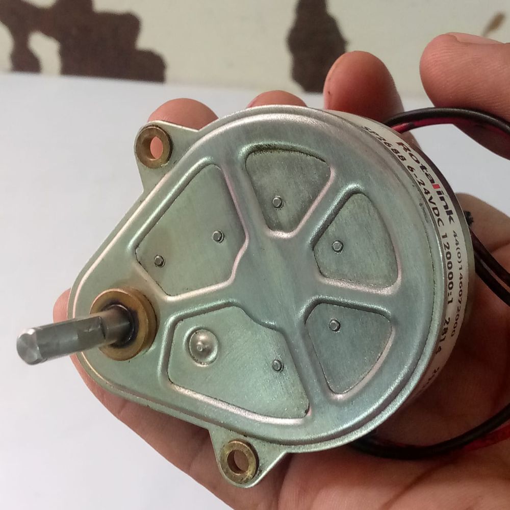 Used High Torque Gearbox Motor SP2688 Xerox 5855 Web Supply Motor - a silver metal geared motor held in a hand, showing the output shaft and printed labels with voltage and ratio specs.