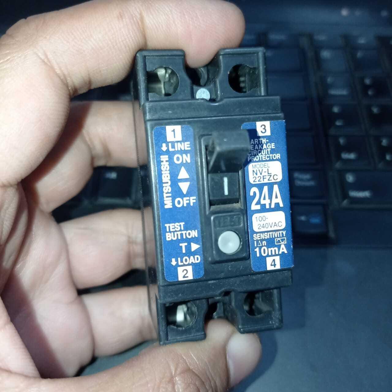 Used Mitsubishi NV-L22FZC 24A Earth Leakage Circuit Breaker Switch - a black rectangular electrical switch held in a hand, featuring a toggle, test button, and labels.