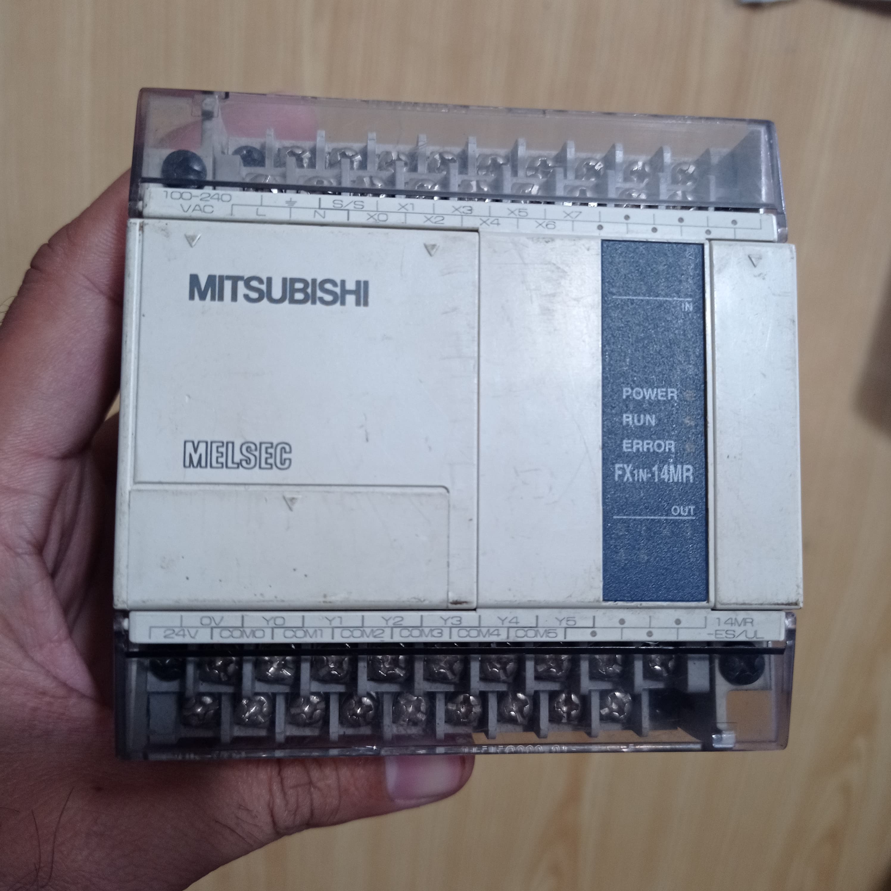Used Mitsubishi PLC Fx1n-14MR-ES/UL - a beige rectangular industrial controller held in a hand, featuring top and bottom screw terminals and status indicators.