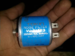 Used Noise Filter EMI Filter Anti-Interference Noise Signal Filtration Single Phase Mains Filter 125V 250V - Tokin Noise Filter VU-215F3, a cylindrical blue EMI filter held in a hand, showing two metal spade terminals on one side and a threaded connector.