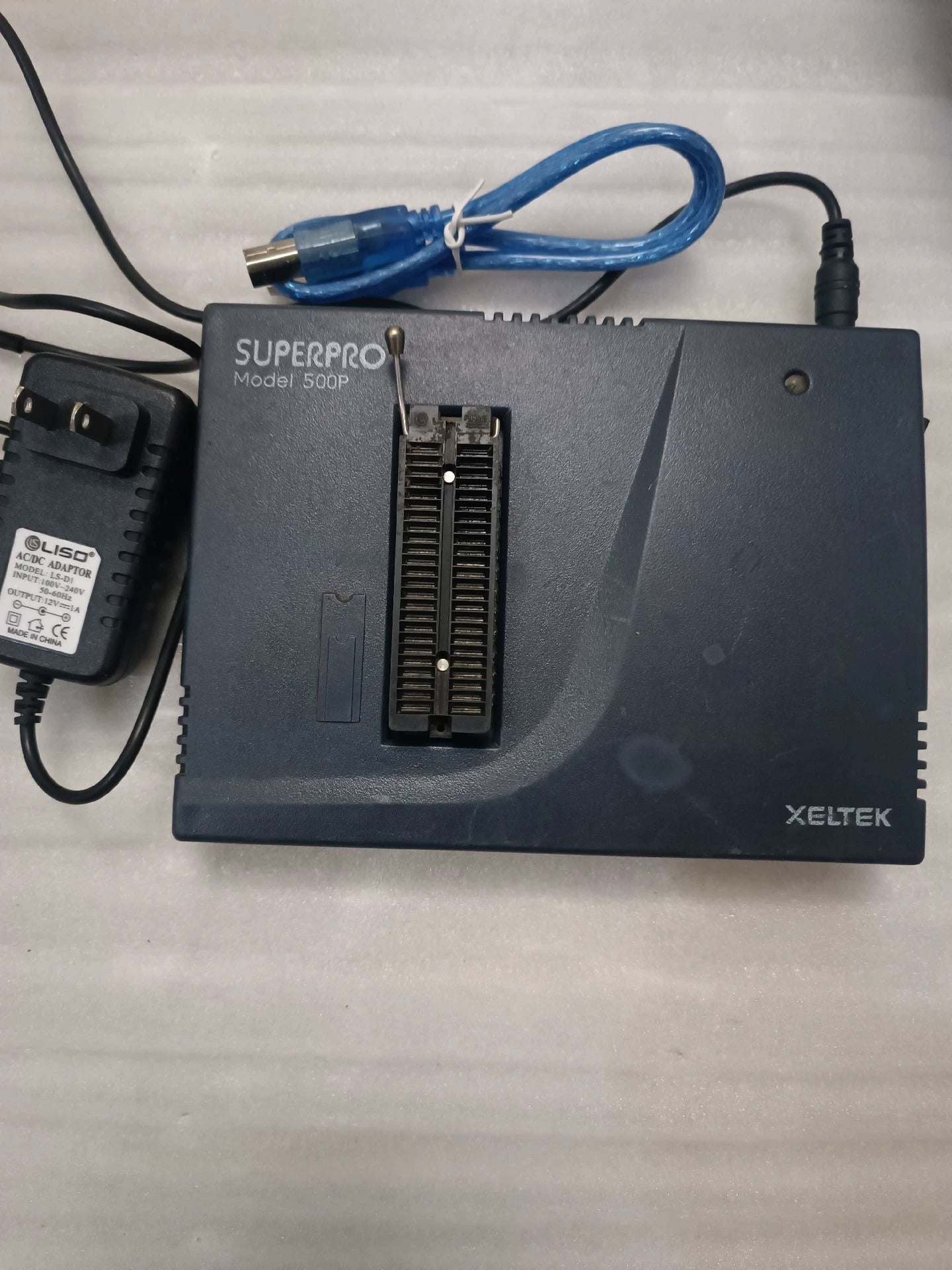 Used SUPERPRO 500P Universal Programmer High-Speed IC Programming - dark grey case with a central ZIF socket, a power adapter, and a blue USB cable on a white surface.