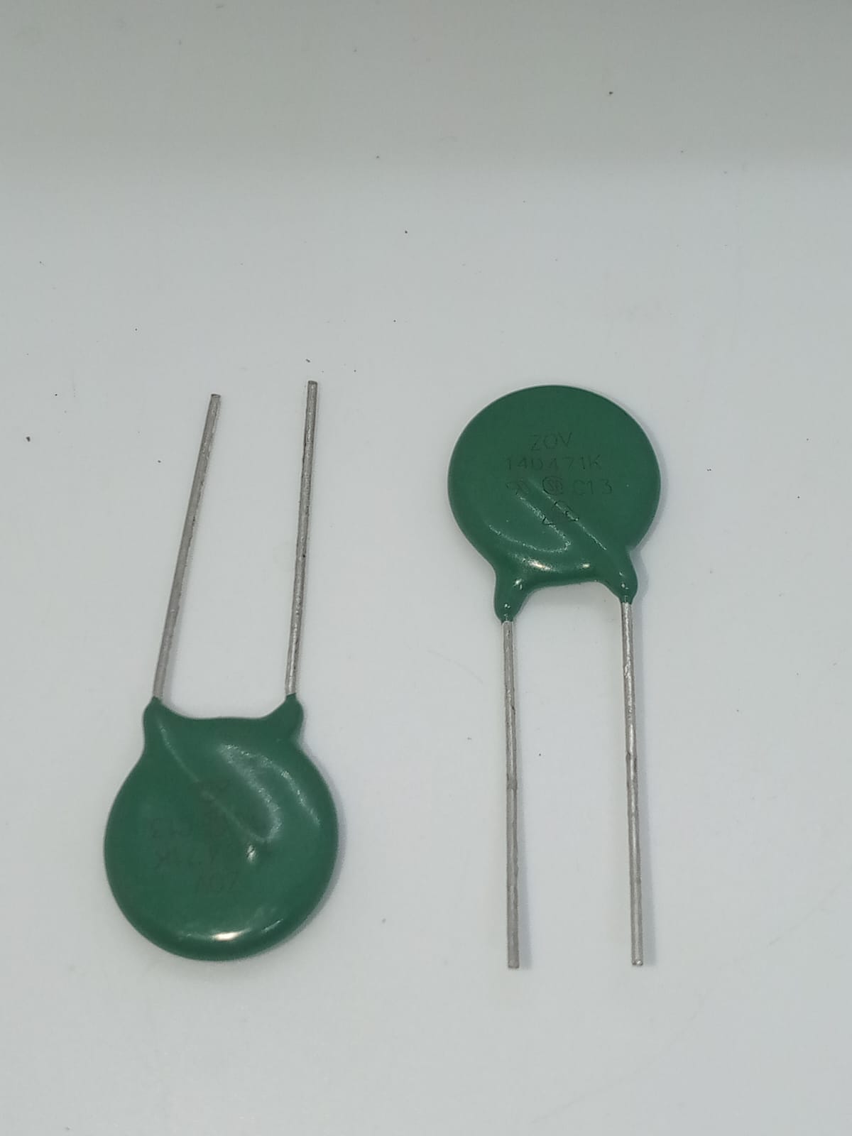 Varistor 14D471K - two green, disc-shaped electronic components with two metal leads each, viewed against a plain white background.