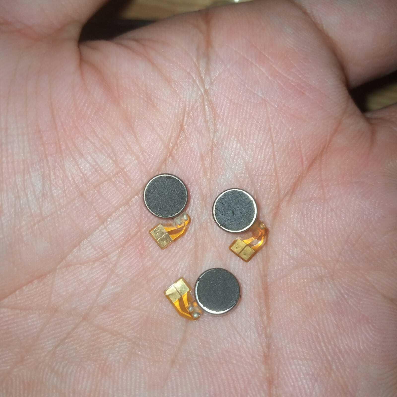 Vibrator Motor DC Mini Vibration Motor - three small, round, silver-cased motors with attached flexible orange ribbon cables held in a palm.