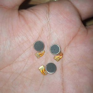 Vibrator Motor DC Mini Vibration Motor - three small, round, silver-cased motors with attached flexible orange ribbon cables held in a palm.