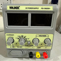VOLDER 1502DD+ Regulated DC Power Supply - VOLDER PS-1502DD+ DC power supply in a grey casing with two blank digital displays, voltage and current control knobs, and black, yellow, and red terminals.
