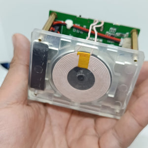 Wireless Charger Tester Smart Watches QI Wireless Charger Tester Voltage Current Load PCB Detector for Apple iWatch Galaxy Watch Wireless Chargers - a transparent square device held in a hand featuring a circular copper induction coil on a green circuit board with brass spacers.