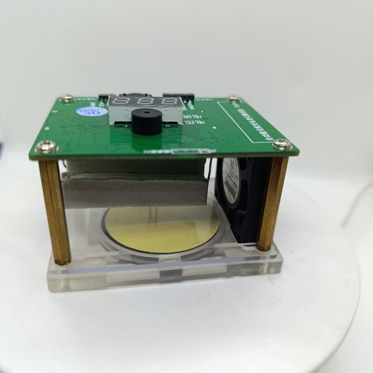 Wireless Charger Tester Smart Watches QI Wireless Charger Tester Voltage Current Load PCB Detector for Apple iWatch Galaxy Watch Wireless Chargers - a green PCB board with a digital display, a black buzzer, and a cooling fan, mounted on brass standoffs over a circular base.