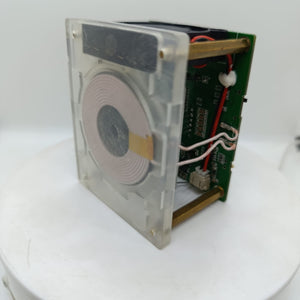 Wireless Charger Tester Smart Watches QI Wireless Charger Tester Voltage Current Load PCB Detector for Apple iWatch Galaxy Watch Wireless Chargers - a circuit board with a copper coil mounted on a clear square frame, connected by two white wires to the green PCB.