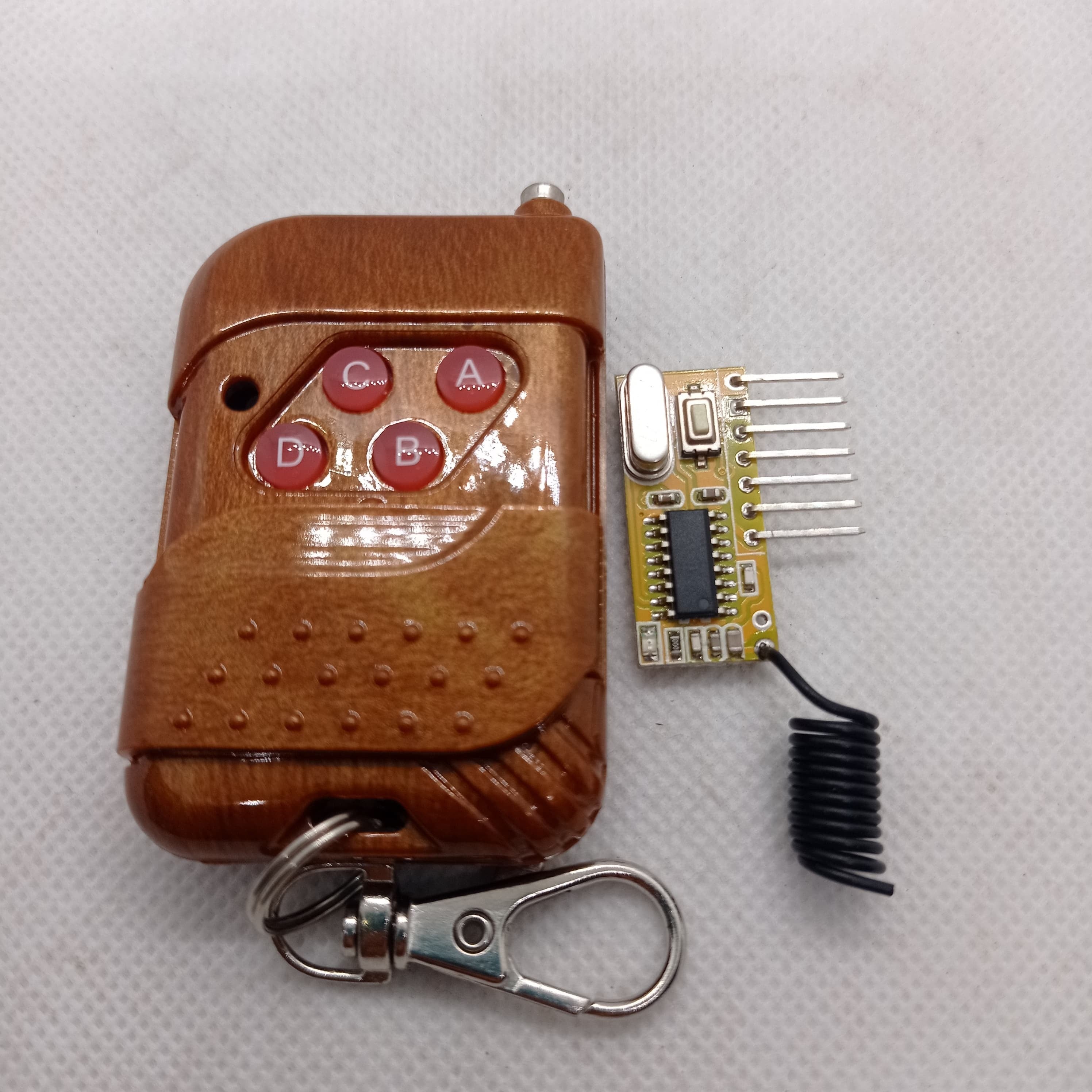 Without Battery 4 Channel Wireless Remote Control Kit RX12 RF Transmitter Receiver Module For Arduino Momentary Type - brown wood-patterned four-button remote transmitter next to a small circuit board receiver with a coiled antenna.