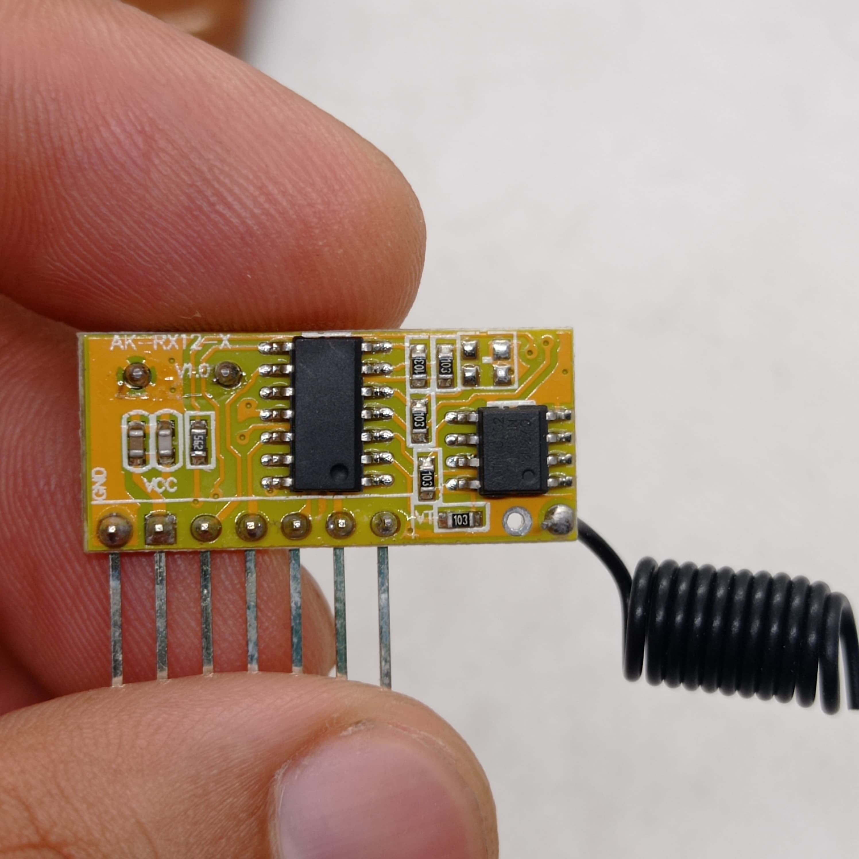 Without Battery 4 Channel Wireless Remote Control Kit RX12 RF Transmitter Receiver Module For Arduino Momentary Type - a close-up of a small yellow circuit board with pins, chips, and a coiled antenna.
