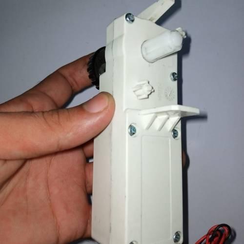 Worm Gear High Torque 12V 5RPM DC Gear Motor - shown in a hand, featuring a white plastic rectangular casing, a rotating output shaft, and red-black wires.