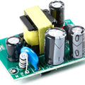 XH-M299 AC-DC Switching Power Supply Module - a green circuit board with a yellow transformer, three electrolytic capacitors, and L, N, and +5V ports.