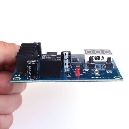 XH-M603-M632 Battery Charging Control Module DC 12V-24V Voltage Charging Discharge Monitor Relay Switch Battery Protection Board - a blue circuit board with a black relay, a red LED, two push buttons, and a digital display held in a hand.